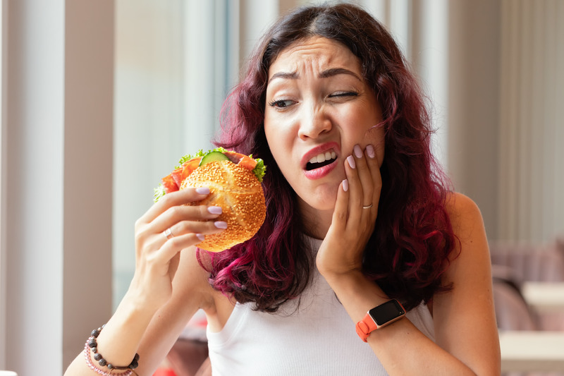 Patient holding their jaw while eating due to TMJ disorder