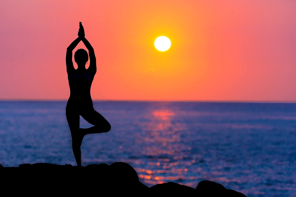 Woman in Tree Pose at Beach in Sunset