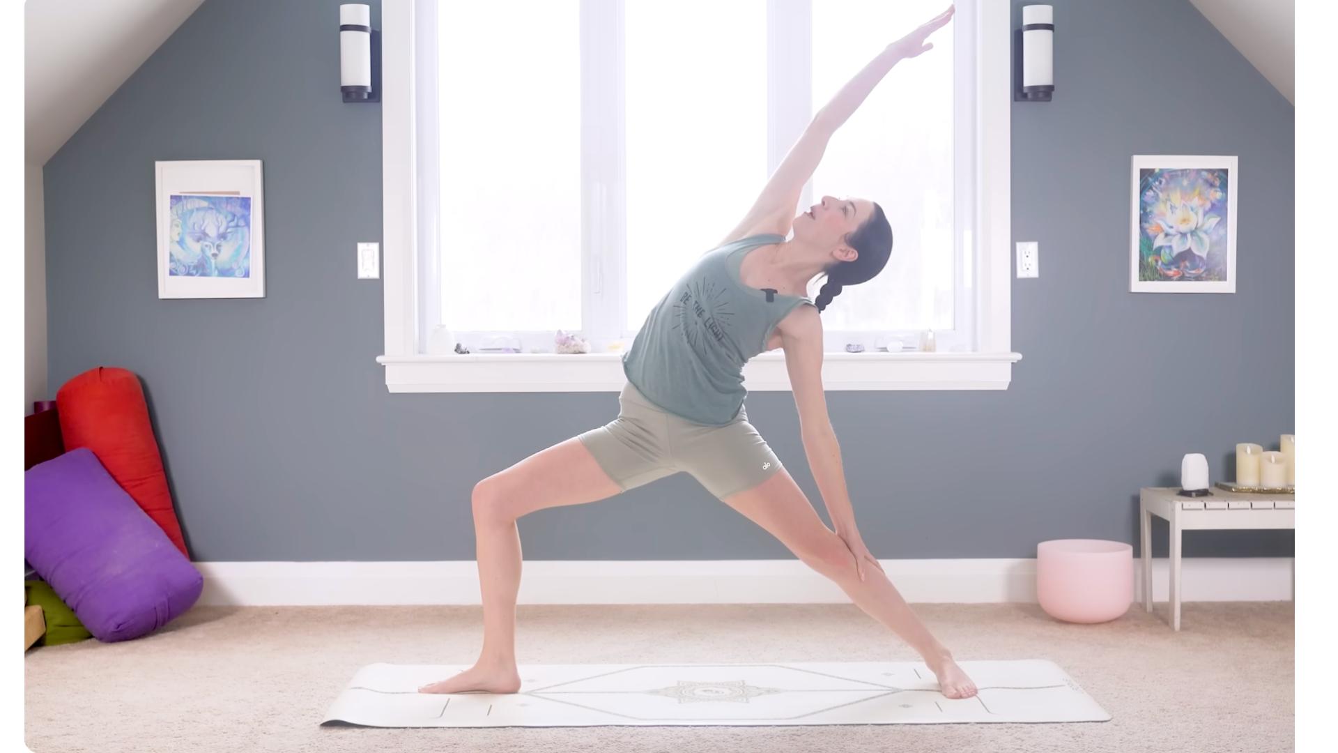 Woman in Reverse Warrior facing the long side of a mat and reaching her right arm alongside her head