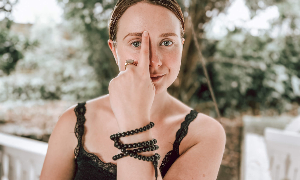 Woman demonstrating how to tap the eyebrow point in EFT, a common face tapping method for reducing anxiety and emotional stress. Targets the start of the bladder meridian.