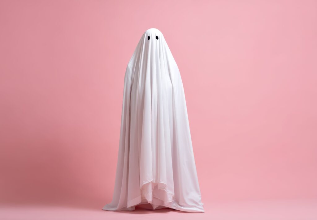 Someone in bed sheet ghost costume with pink background