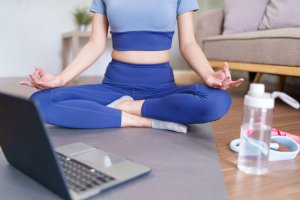 woman on yoga mat with laptop