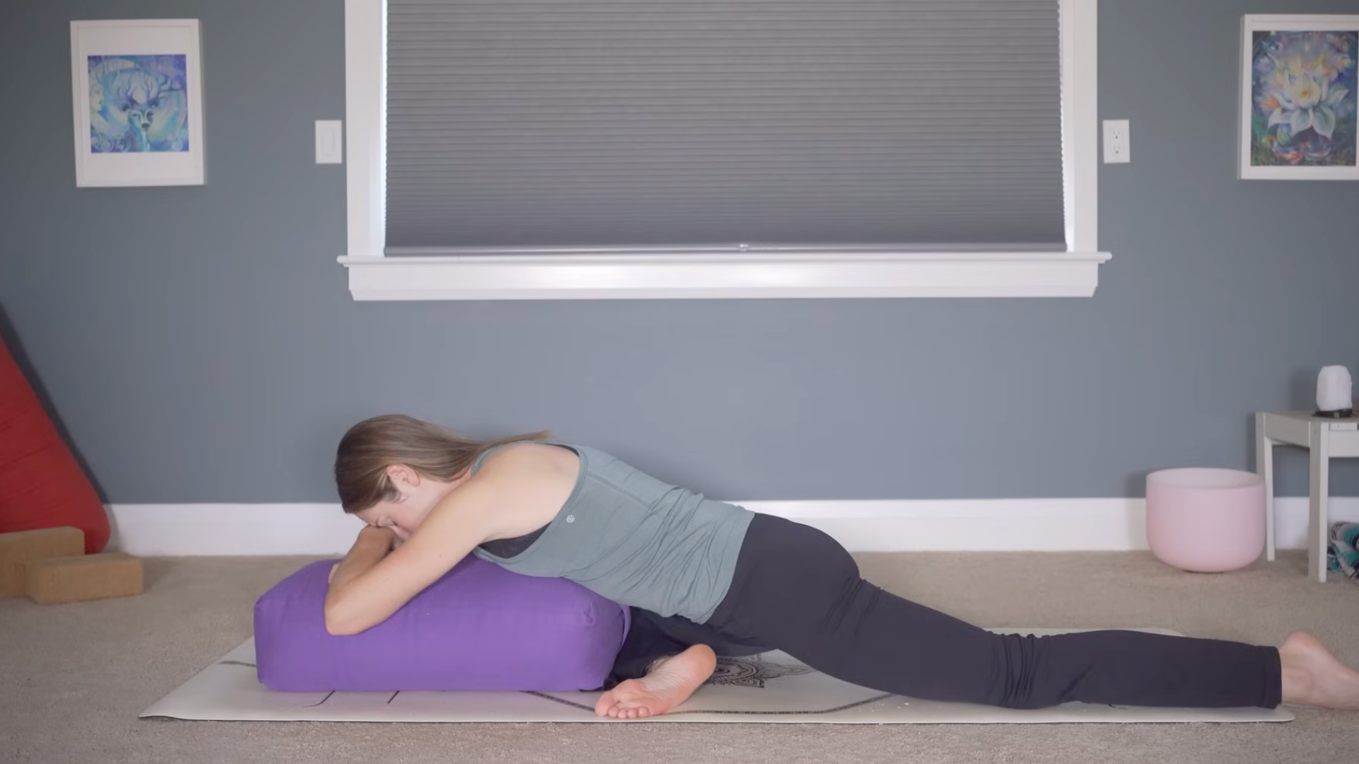 Woman with her belly down on a bolster in Pigeon Pose