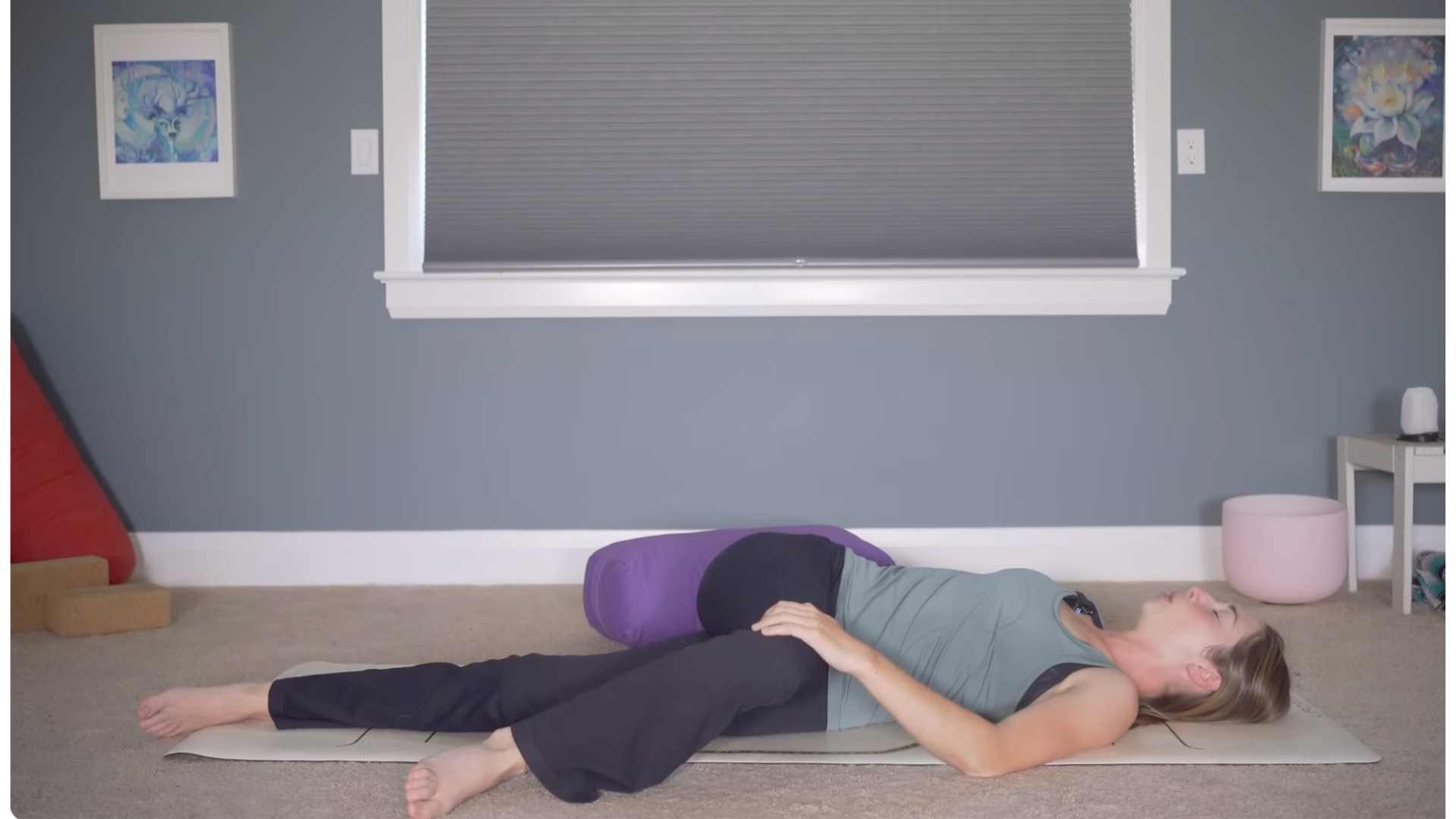 Woman lying on her back in a reclined twist on a yoga mat