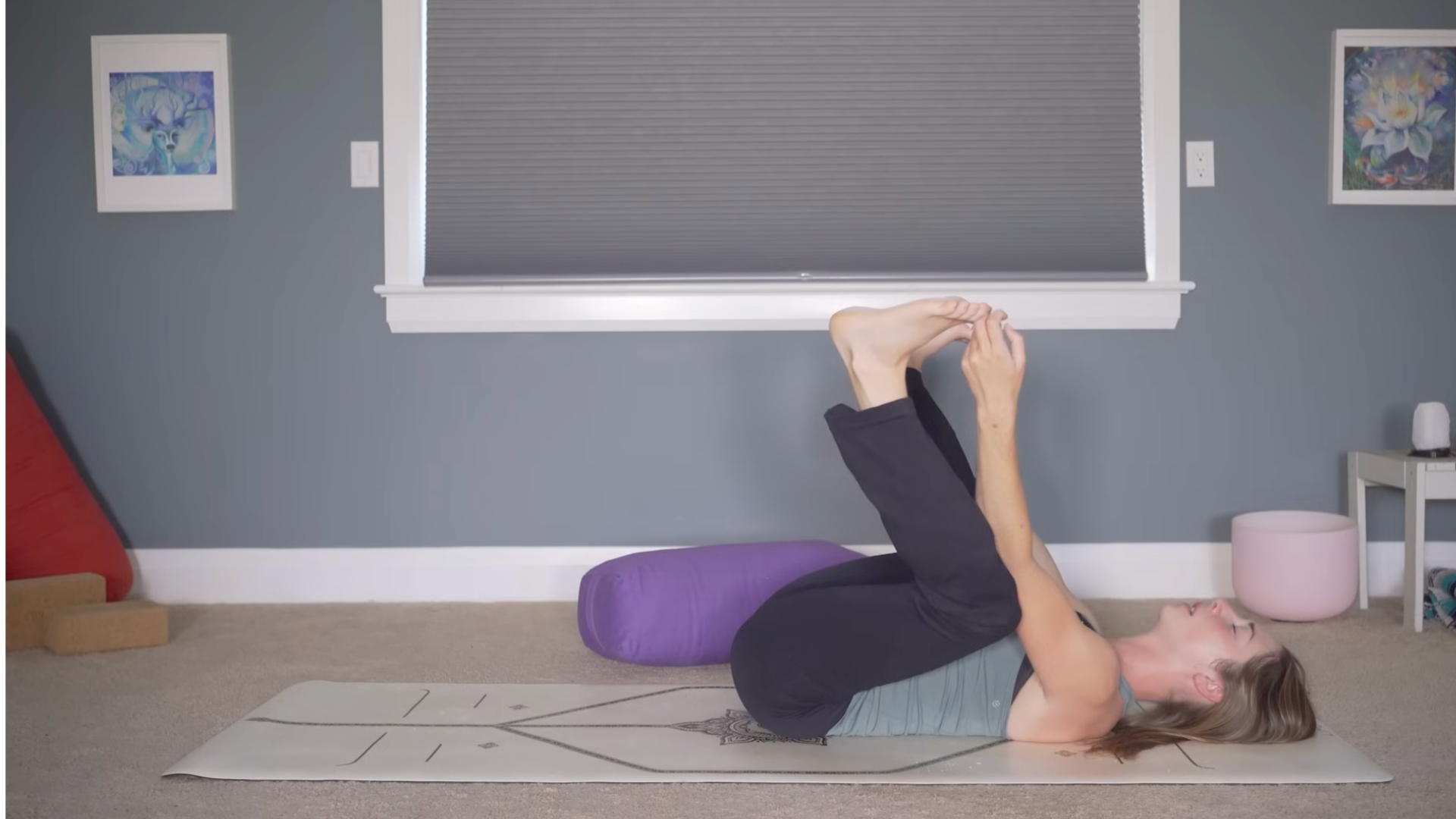 Woman lying on her back with her knees bent and her hands gripping her toes