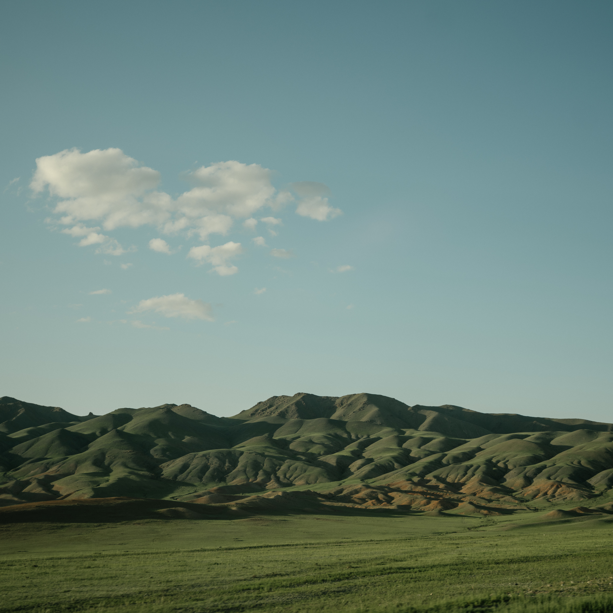 A wide view of grassy Mongolian foothills.
